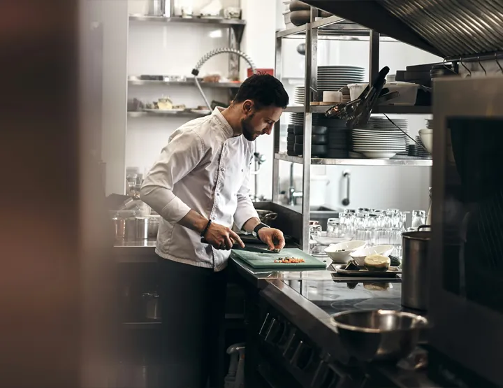 A chef chops vegetables in a commercial kitchen