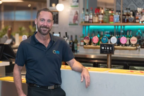 A person in a CTA Training Specialist polo leans on a bar.