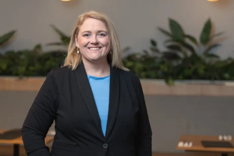 A woman smiles at camera. she is wearing blazer.