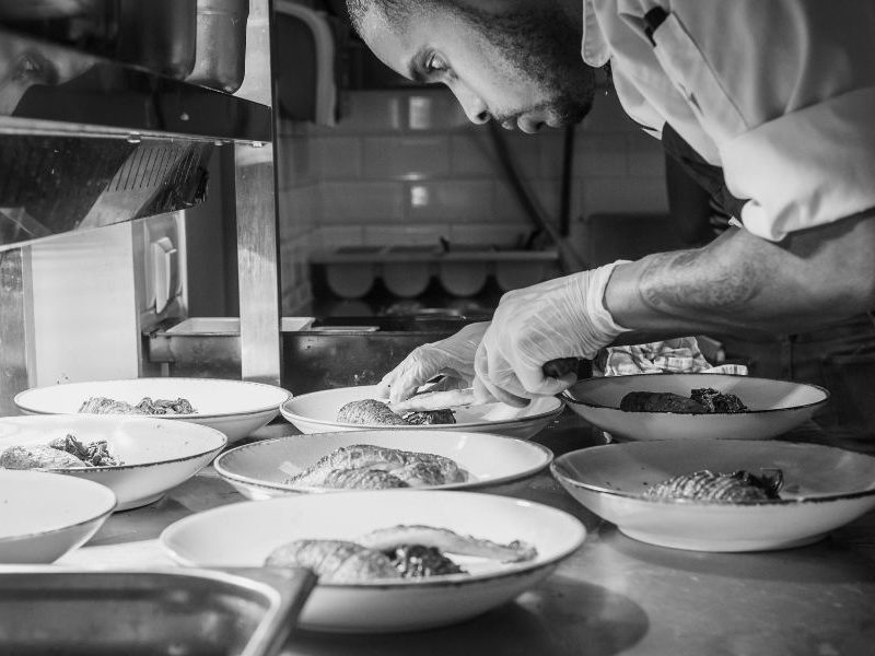 A black and white photo of a chef preparing dishes.