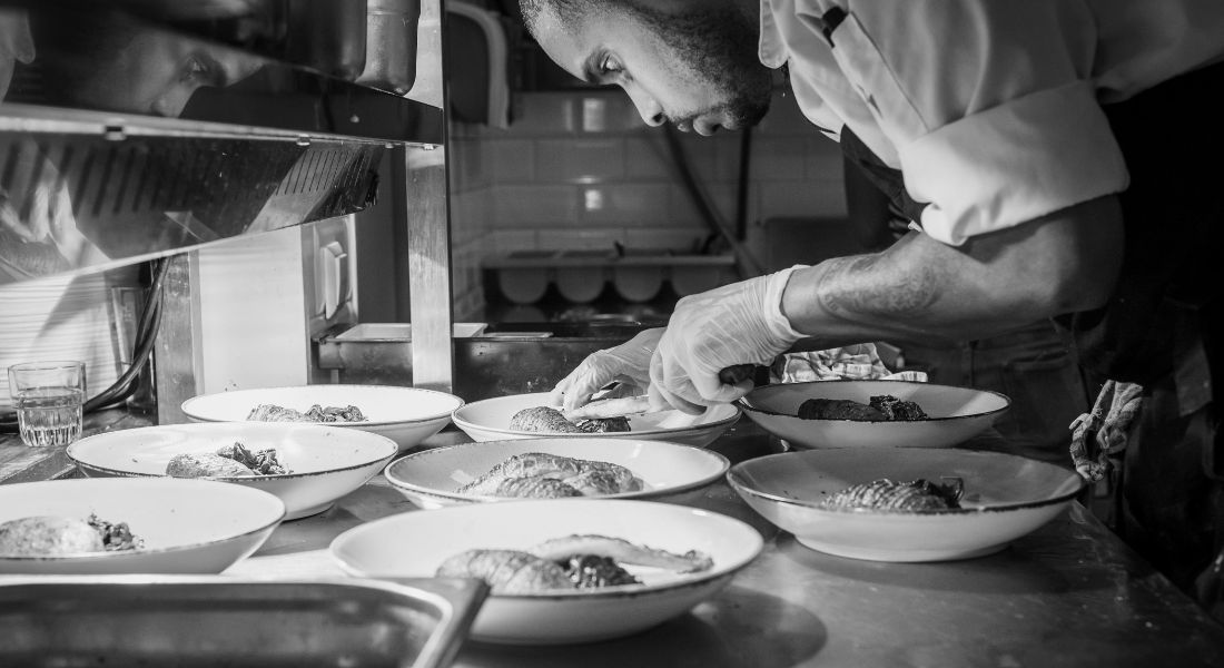 A black and white photo of a chef preparing dishes.