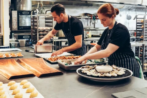 Two chefs prepare food together. Photo by Elle Hughes.