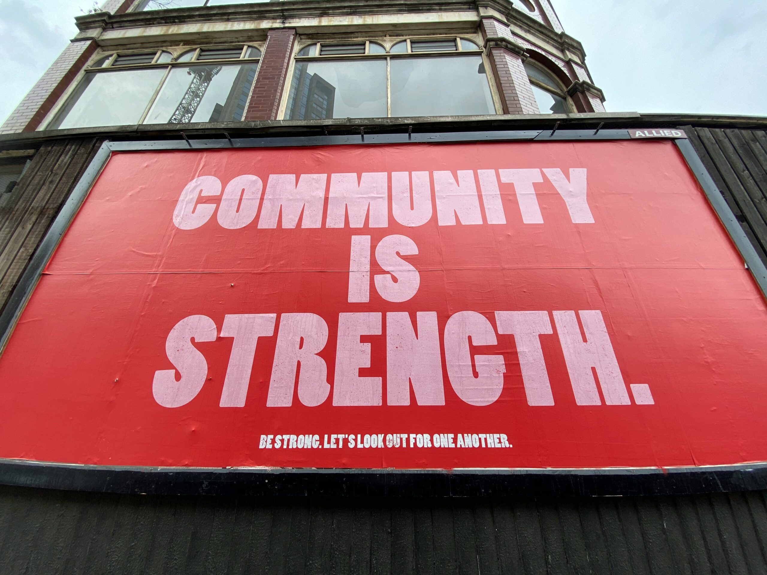 A red and white sign saying 'Community is Strength'