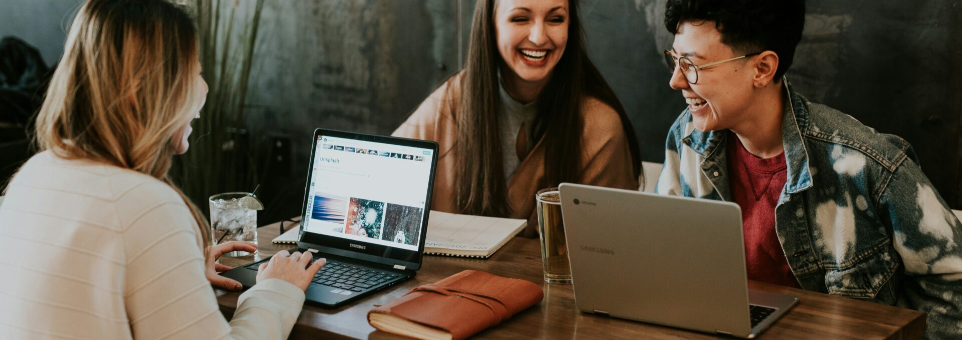 Three people laugh at a desk